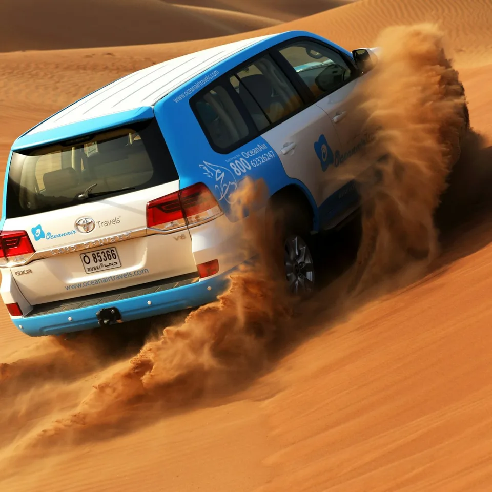 Blue four-wheel-drive vehicle driving across Dubai sand dunes