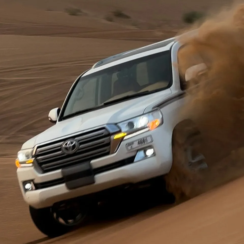 Four-wheel-drive vehicle descending a sandy desert dune