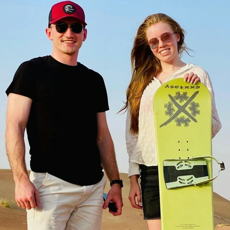 Guests holding sandboards in the desert