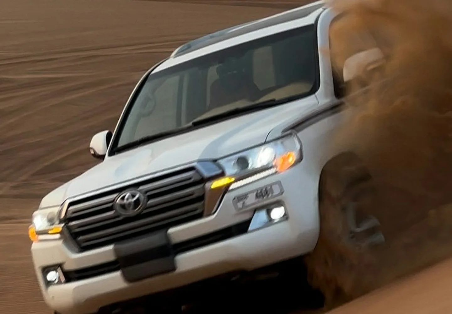 Four-wheel-drive vehicle descending a sandy desert dune